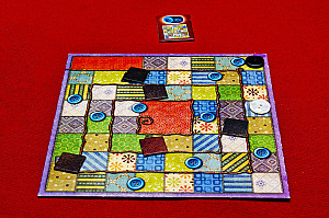 Игровое поле и жетон, который получает игрок,  первый заполнивший на своем планшете квадрат 7x7 клеток